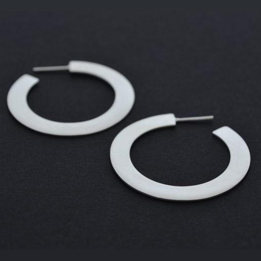 hoop silver earrings flat and wide shape yet light. Modern chic style for an urban look. Everyday jewelry