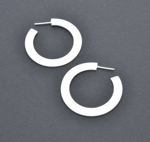 hoop silver earrings flat and wide shape yet light. Modern chic style for an urban look. Everyday jewelry